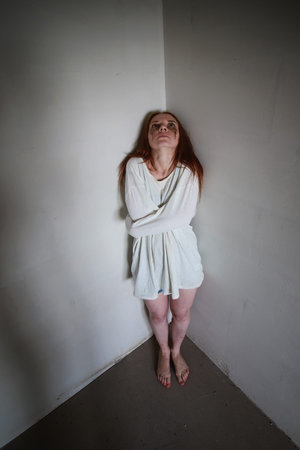 Portrait of a young red-haired girl on a background of gray plaster wall