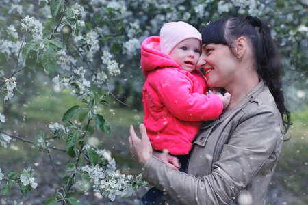 Happy beautiful girl of European appearance with her baby in the parkの写真素材