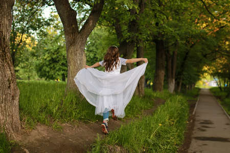 teenager on a sunny spring day walking in a park and blows away dandelion flowersの写真素材