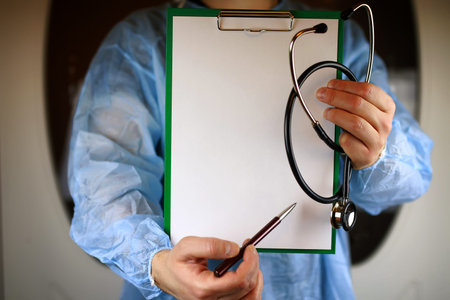 Doctor in blue robe holding a tablet for notes and a stethoscope in the hands ofの写真素材
