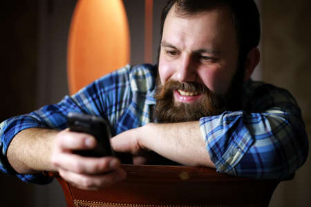 bearded handsome man sitting on a chair and posing for the cameraの写真素材