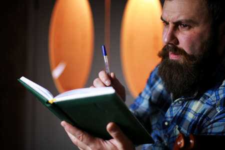 bearded handsome man sitting on a chair and posing for the cameraの写真素材