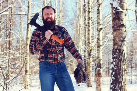 bearded handsome man went into the forest with an ax to produce wood for the furnaceの写真素材