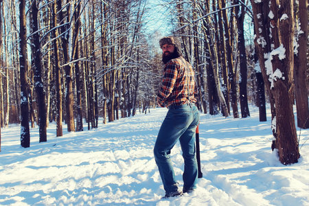 bearded handsome man went into the forest with an ax to produce wood for the furnace
