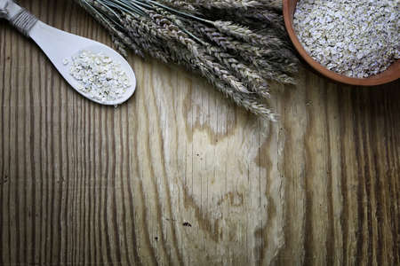 milled wheat in clay pots on a wooden table and a bouquet of dry wheatの写真素材