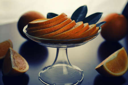ripe fresh juicy oranges sliced on a glass plateの写真素材