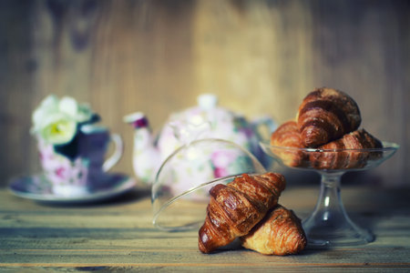 small freshly baked croissant and cup of hot flavored tea on the tableの写真素材