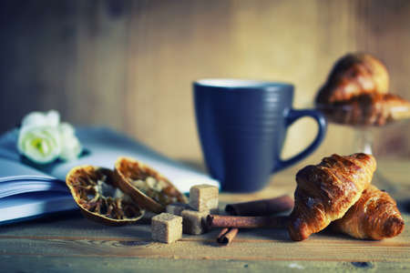 small freshly baked croissant and cup of hot flavored tea on the tableの写真素材