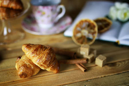 small freshly baked croissant and cup of hot flavored tea on the tableの写真素材