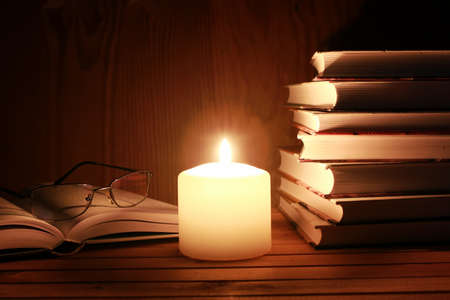 book and glasses on a table with candle light in nightの写真素材