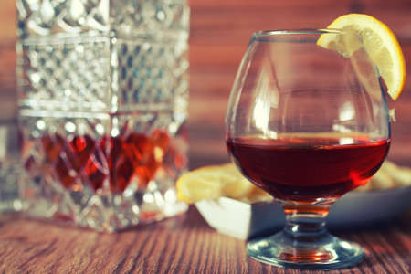 glass with sustained strong alcohol brandy on a wooden tableの写真素材