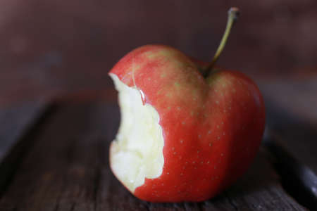red bitten apple on an old  wooden backgroundの写真素材