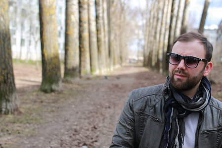 bearded trendy handsome young man walking in the park in springの写真素材