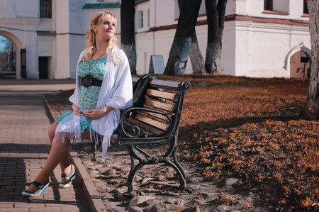 cute beautiful blonde pregnant woman walks in the park in the spring afternoonの写真素材