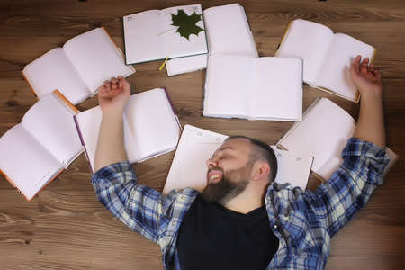man lying on the floor with booksの写真素材