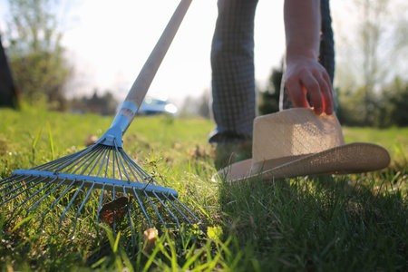 man with a lawn rake cleans the country of excess debrisの写真素材