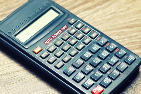 gray business calculator on a wooden table and a stack of money for the calculation of the amount of utility bills paymentの写真素材