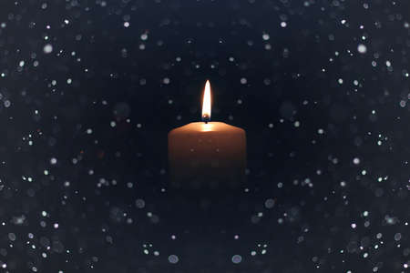 bright flame of a burning candle on a black background on the eve of New Year holidaysの写真素材