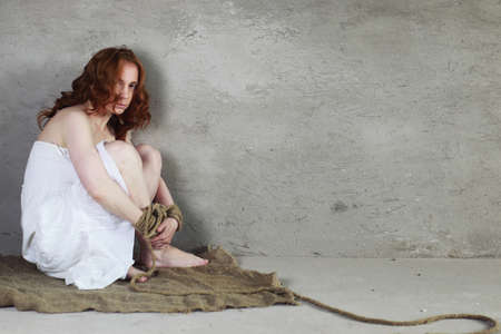 Portrait of a young red-haired girl on a background of gray plaster wallの写真素材