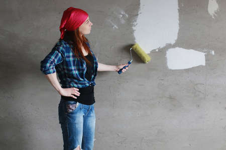 Portrait of a young red-haired girl on a background of gray plaster wallの写真素材