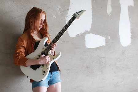 Portrait of a young red-haired girl on a background of gray plaster wall