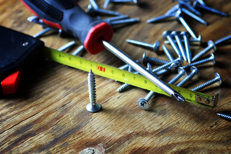 long silver screws and screwdriver on a wooden table textural joineryの写真素材