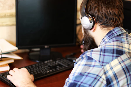 bearded man sitting at a table and working with a laptopの写真素材