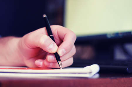 bearded man sitting at a table and working with a laptopの写真素材