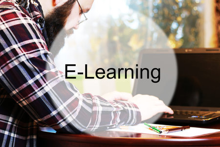 bearded man sitting at a table and working with a laptopの写真素材