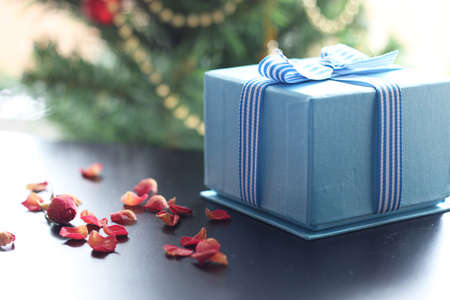 Christmas gift in the blue box with a bow with a bright-colored toysの写真素材