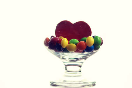 colored jelly beans and candy in a glass transparent glass on a tableの写真素材