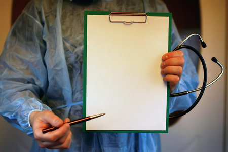 Doctor in blue robe holding a tablet for notes and a stethoscope in the hands of