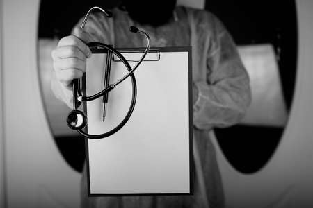 Doctor in blue robe holding a tablet for notes and a stethoscope in the hands ofの写真素材