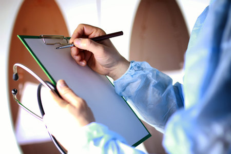 Doctor in blue robe holding a tablet for notes and a stethoscope in the hands ofの写真素材
