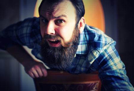 bearded handsome man sitting on a chair and posing for the cameraの写真素材