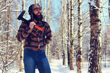 bearded handsome man went into the forest with an ax to produce wood for the furnaceの写真素材