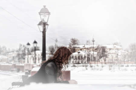 girl with red hair posing in the street at the rail of a winter dayの写真素材