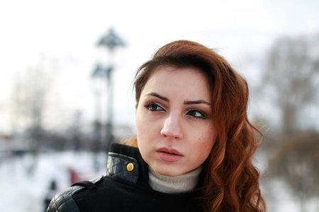 girl with red hair posing in the street at the rail of a winter day