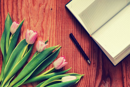 still life on the texture old wooden table bouquet of beautiful tulips an open book