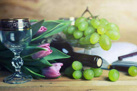Still on the table a bottle of wine and a bouquet of beautiful pink rosesの写真素材