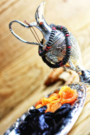 Dried oriental fruit on a silver tray on a wooden table lightの写真素材