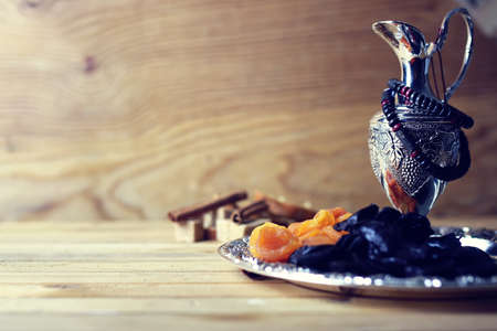 Dried oriental fruit on a silver tray on a wooden table lightの写真素材
