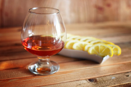 glass with sustained strong alcohol brandy on a wooden tableの写真素材