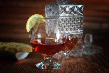 glass with sustained strong alcohol brandy on a wooden tableの写真素材