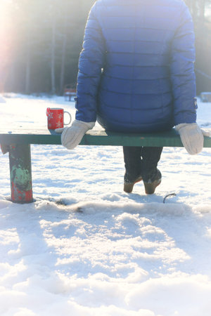 Pretty red-haired girl in the winter forest walks in the snow on a sunny dayの写真素材