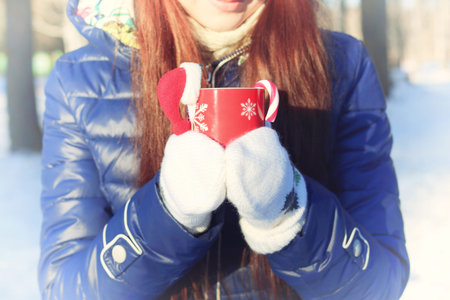 Pretty red-haired girl in the winter forest walks in the snow on a sunny dayの写真素材