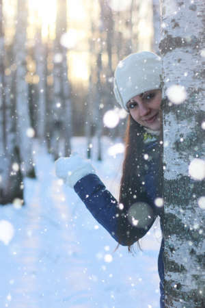 Pretty red-haired girl in the winter forest walks in the snow on a sunny dayの写真素材