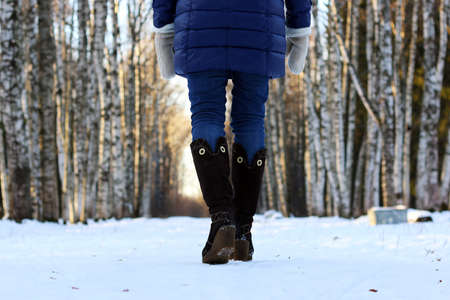 Pretty red-haired girl in the winter forest walks in the snow on a sunny dayの写真素材