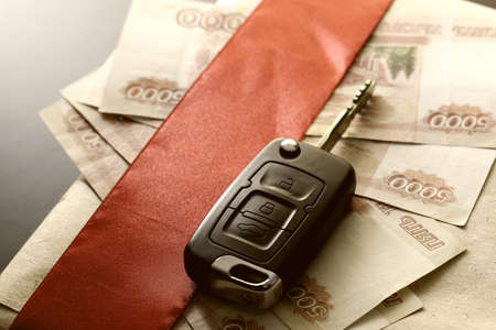 Black keychain car key on a matt black background and moneyの写真素材