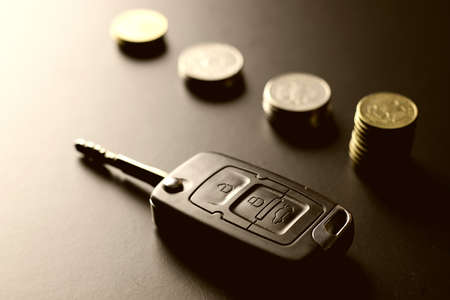 Black keychain car key on a matt black background and moneyの写真素材